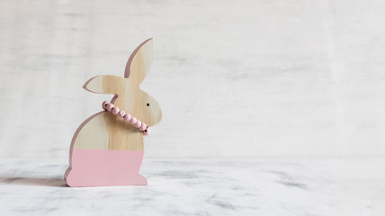 Pink figure of Easter rabbit made of wood on a white vintage background. Easter postcard. Copy space.