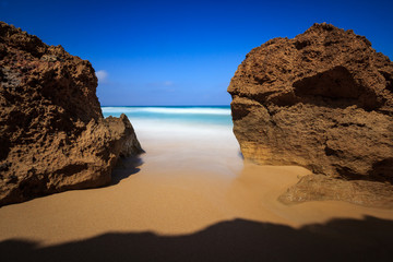 Fototapeta na wymiar deux rochers sur la plage de sable et vue sur mer