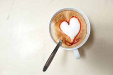 A cup of coffee with a heart pattern on a vintage table