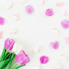 Floral round frame with pink tulips with petals and marshmallow on white background. Flat lay, Top view.