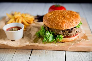 American burger with grilled beef, salad, cheese and tomato on dark background