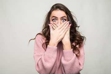 Portrait of a happy young woman covering her mouth isolated on a white background.
