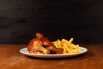roasted half chicken, traditional bavarian dish with french fries on wooden table, and black copy space