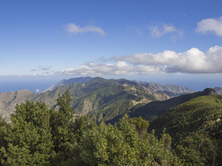 Fototapeta premium view point Amogoje, green hills with rock in the sea El Draguillo in anaga mountain, tenerife canary island spain with dramatic blue sky white clouds background