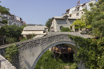 Kriva Cuprija ancient bridge in Mostar, surrounded by city old buildings