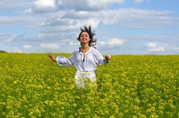 Fototapeta premium beautiful young girl in a white dress in a field of flowers