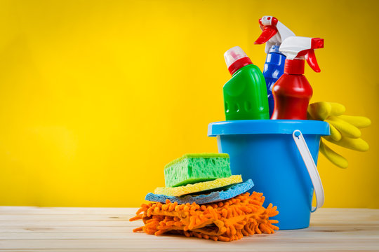 Cleaning concept - cleaning supplies on wood background