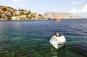 Fototapeta na wymiar A lonely boat on the shore against the background of the city of Symi.
