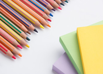 colored pencils and paper for notes on a white office desk