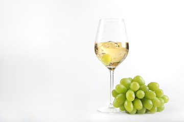 Weiswein in einem Glas mit einer Traube im Glas und Weintrauben nebenliegend