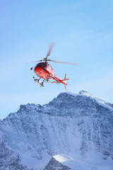 Fototapeta na wymiar Red helicopter at Swiss Alpine mountains in winter Gsteigwiler