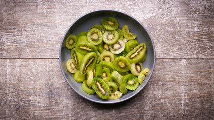 kiwi in a plate on a wooden background