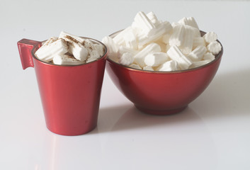 A Cup of coffee or hot chocolate with marshmallows and a red plate on a white background. Close up. Christmas photo. 