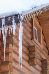 icicles hang from the roof of the winter the ice is frozen water, wooden house