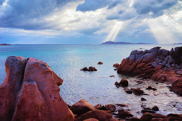 Sun under clouds on Capriccioli Beach in Sardinia