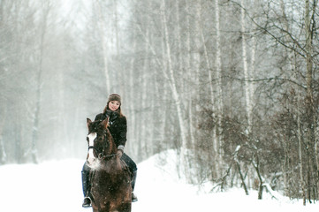 Female rider and horse in the open air. portrait of a beautiful young woman with her stallion, outdoors in winter