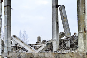 Fototapeta premium Remains of the destroyed industrial building. Large concrete piles continue to hold the body of the large concrete buildings, while others look at the sky.