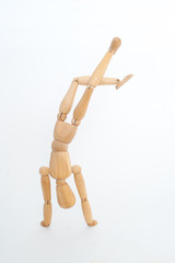 Wooden manikin performs break-dance movement. On a white background.
