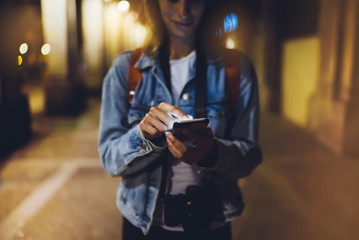 Woman pointing finger on blank screen smartphone on background bokeh light in night atmospheric city, blogger hipster using in hands gadget mobile phone closeup, mockup online wifi internet concept
