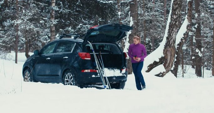 Caucasian female resting on a SUV trunk after cross-country ski training. 4K UHD 60 FPS SLO MO