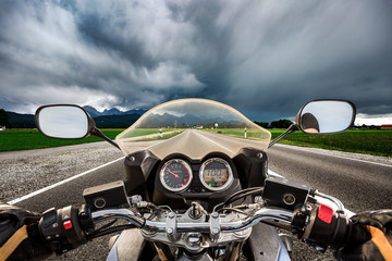 Biker on a motorcycle hurtling down the road in a lightning storm - Forggensee and Schwangau,...