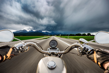 Biker on a motorcycle hurtling down the road in a lightning storm - Forggensee and Schwangau,...