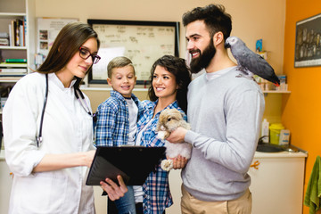 Happy family with rabbit and parrot at veterinary.