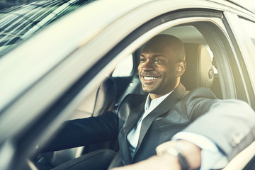 African businessman smiling while driving his car in the city