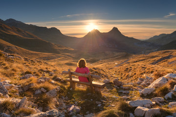 Woman on bench looking out at view of the mountain landscape