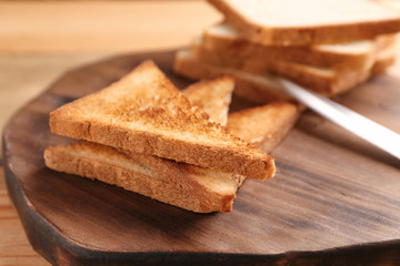 Wooden board with tasty toasted bread, closeup