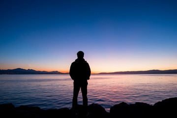 Silhouette of man standing on the rock during sunset