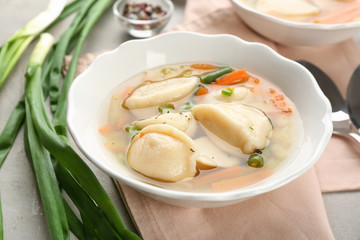 Tasty broth with dumplings on table