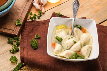 Bowl with tasty broth and dumplings on table