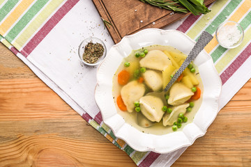 Plate with tasty broth and dumplings on table