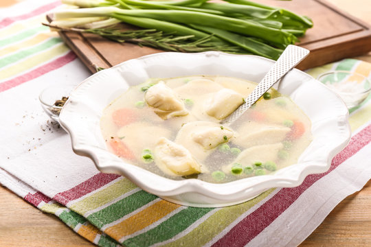 Plate with tasty broth and dumplings on table