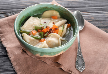 Bowl with tasty broth and dumplings on table
