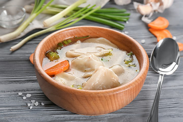 Bowl with tasty broth and dumplings on table