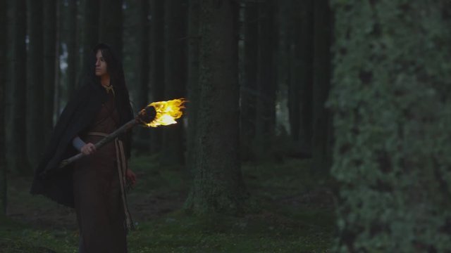 Woman holding a fire staff in the woods