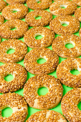 Round cookies with sesame seeds on a bright green background.