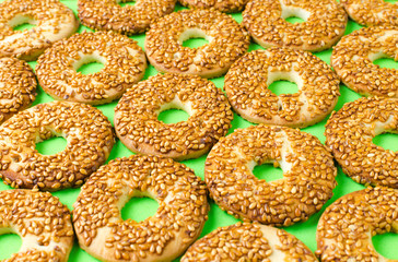 Round cookies with sesame seeds on a bright green background.
