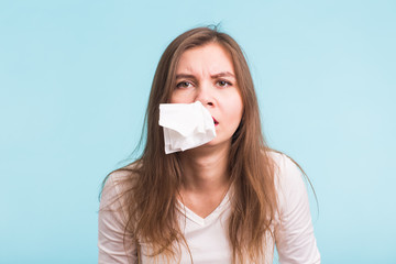 Young woman has a runny nose on blue background