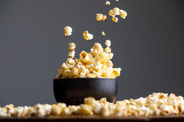 Levitating falling popcorn in a ceramic cup and around it. - obrazy, fototapety, plakaty