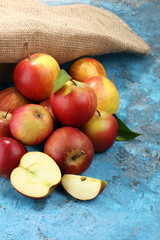 Ripe red apples with leaves on blue background.