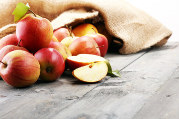 Ripe red apples with leaves on wooden background.