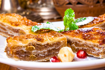 Baklava with honey and nuts on white plate