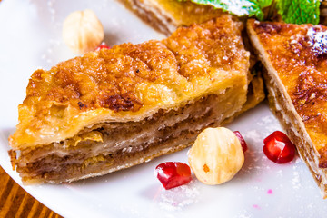 Baklava with honey and nuts on white plate