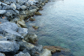 Close up of  a calm sea water and a rocky shore on a summer day