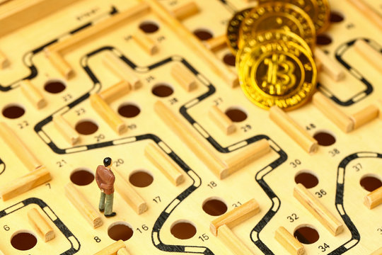 business man standing on wooden maze looking at a pile of bitcoins faraway