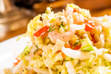 Salad with cabbage, shrimp and avocado on white plate. Close-up