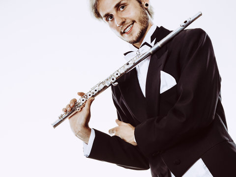 Male flutist wearing tailcoat holds flute